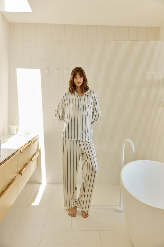 Woman in Harlow Bamboo Striped pyjama PJ Set Ivory model standing in a modern bathroom.