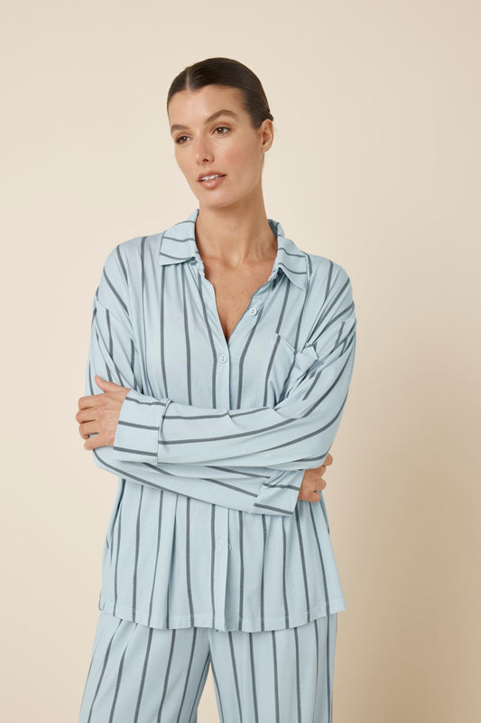 Woman wearing a light blue Harlow Bamboo Striped pyjama PJ Set from a close up view of the top and part of the pants with her arms crossed