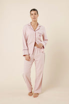 Woman wearing light pink isabella brushed cotton pyjama PJ set with a small red logo on a beige background front on view