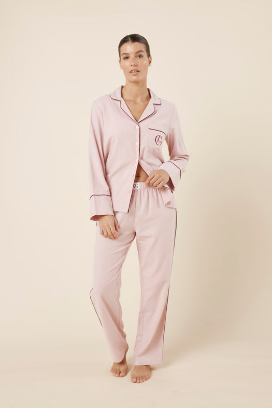 Woman wearing light pink isabella brushed cotton pyjama PJ set with a small red logo on a beige background front on view