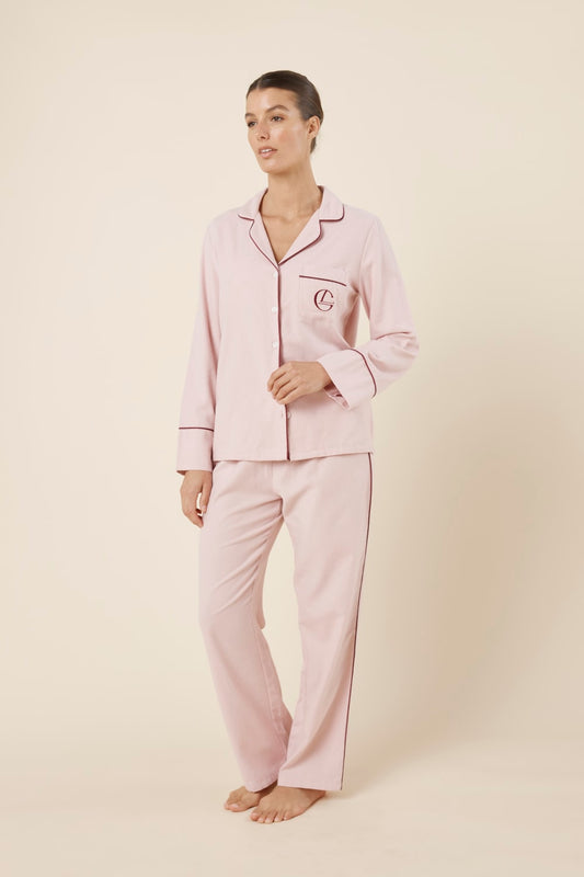 Woman wearing light pink isabella brushed cotton pyjama PJ set with a small red logo on a beige background side on view
