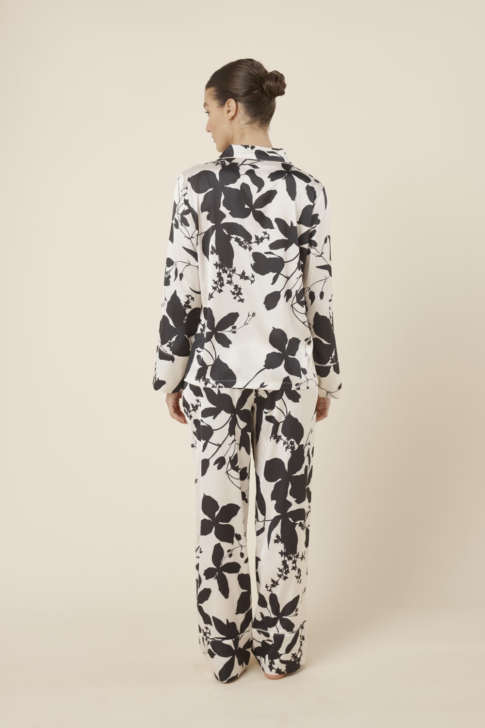 Back view of a woman wearing a black floral ivy silky satin pyjama PJ set including top and bottom