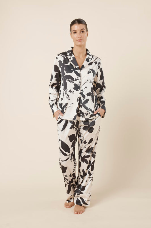 Woman wearing a black and white floral Ivy Silky Satin pyjama PJ set front on view with hands in pockets