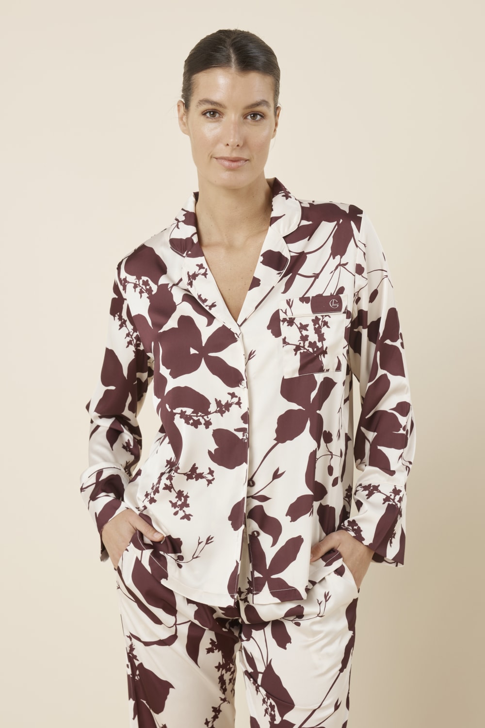 Woman front on cropped view wearing the Ivy Silky Satin pyjama PJ set featuring the floral pattern with hands in pockets