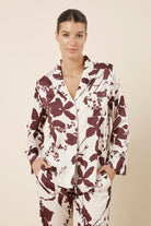 Woman front on cropped view wearing the Ivy Silky Satin pyjama PJ set featuring the floral pattern with hands in pockets