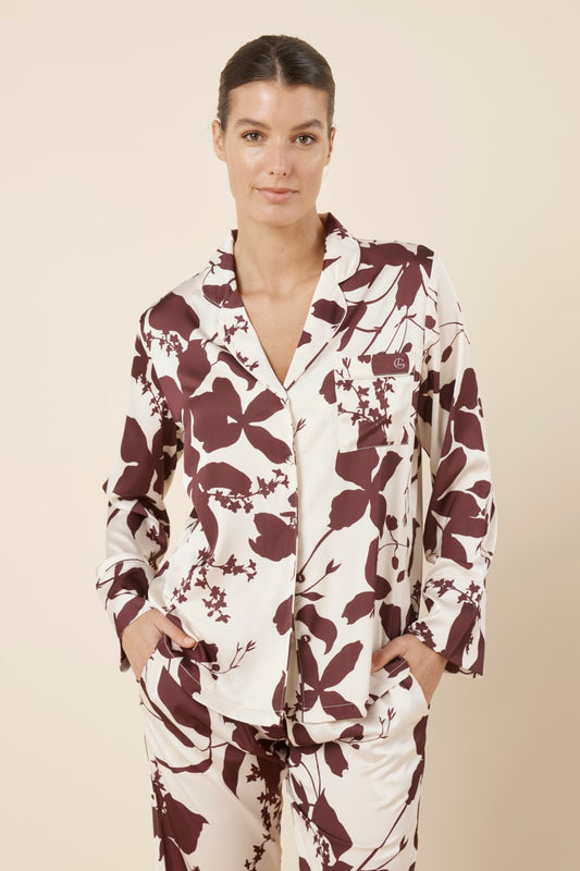 Woman front on cropped view wearing the Ivy Silky Satin pyjama PJ set featuring the floral pattern with hands in pockets