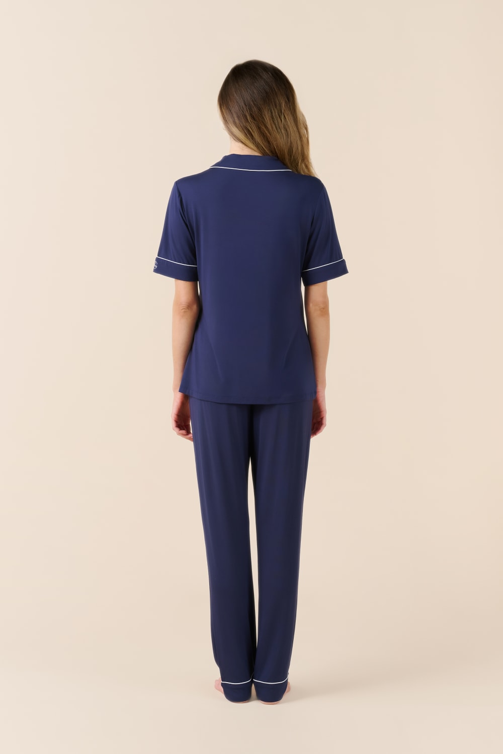 Woman wearing a navy blue pajama set on a beige background