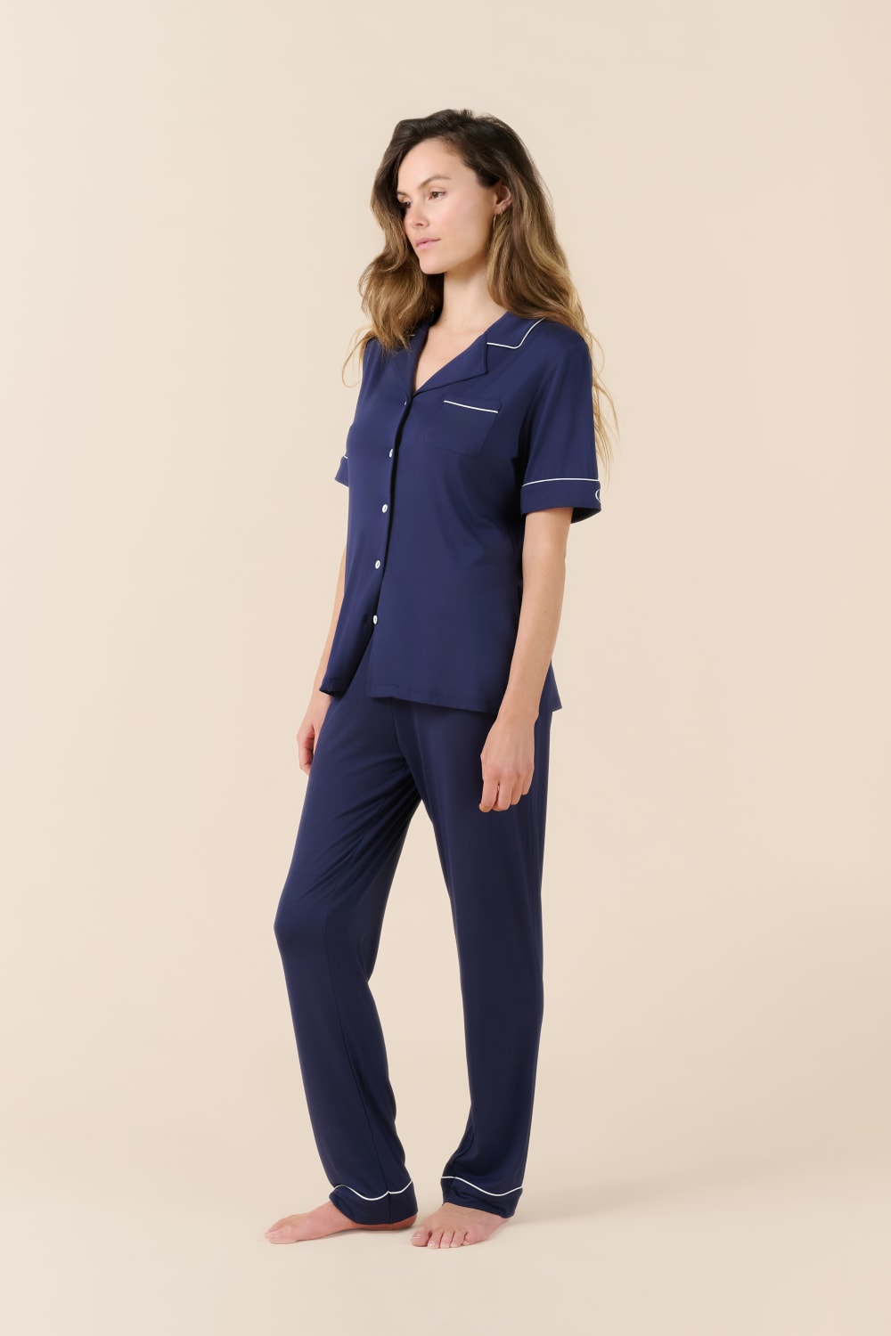 Woman wearing a navy blue pajama set on a beige background