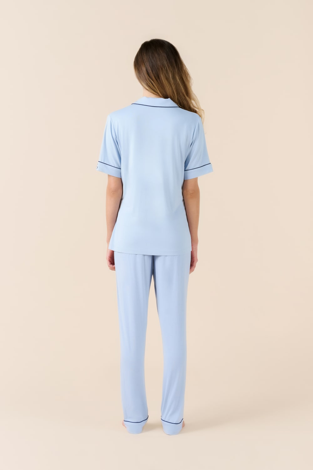 Woman wearing a light blue pajama set on a beige background