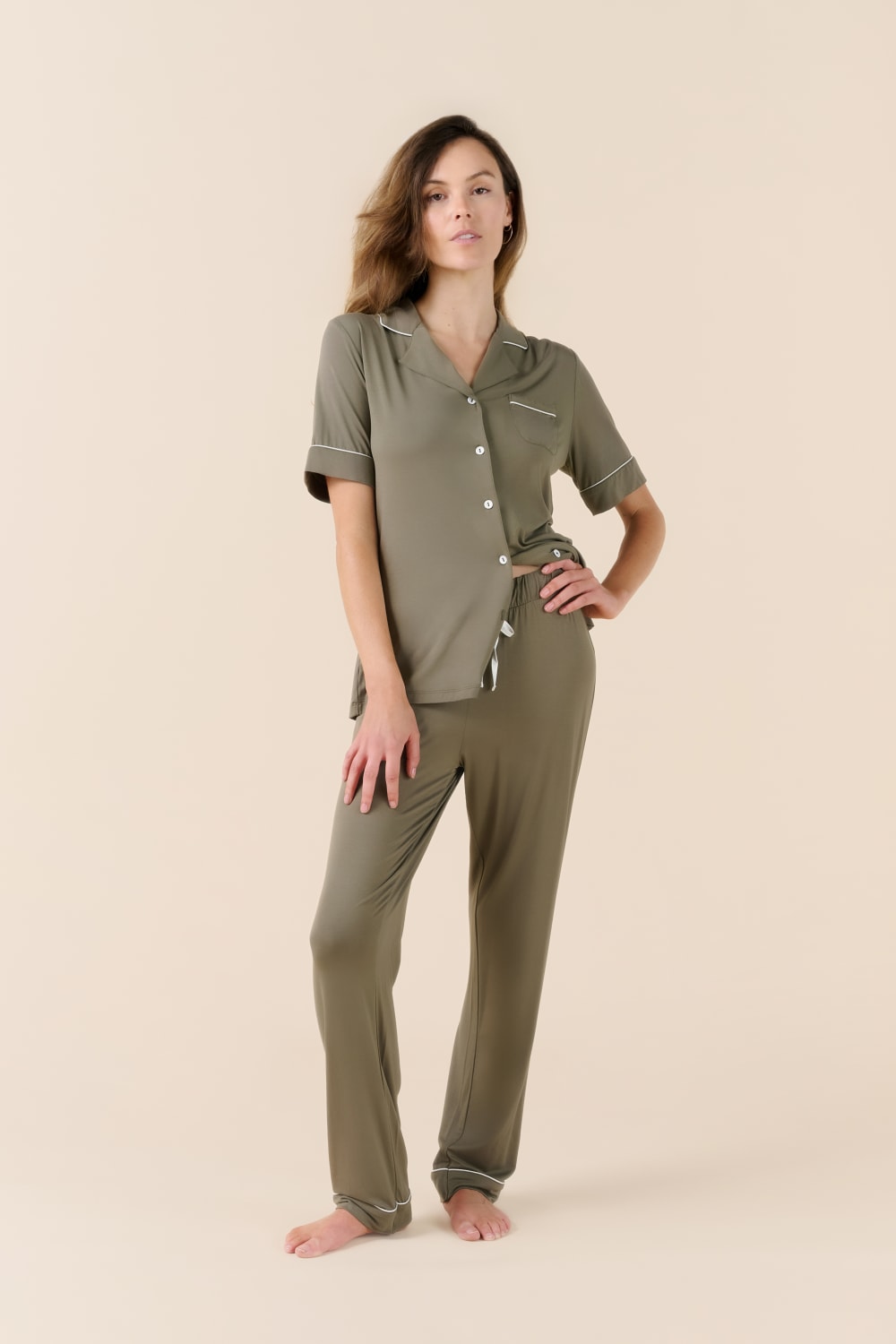 Woman wearing a green pajama set on a beige background