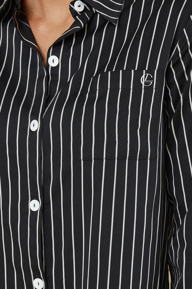 Black and white striped shirt with a brand logo on a neutral background