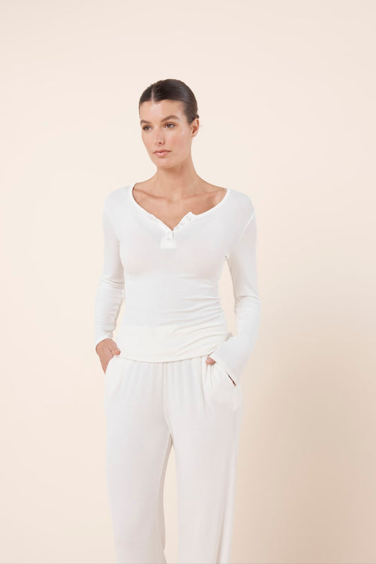Woman wearing Lille Ribbed Long Sleeve Henley Top Ivory Ecru front view showing fitted ribbed fabric and henley button detail