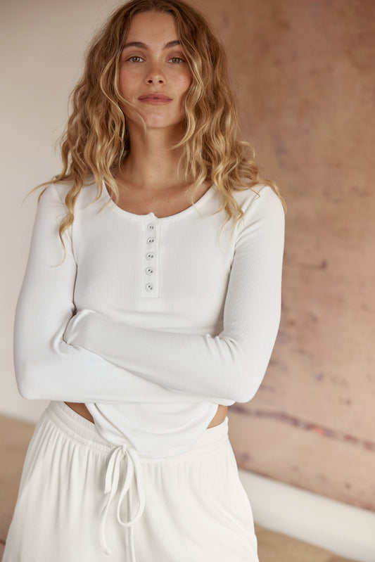 Woman wearing Lille Ribbed Long Sleeve Henley Top Ivory Ecru, ribbed long sleeve henley lounge top with button neckline