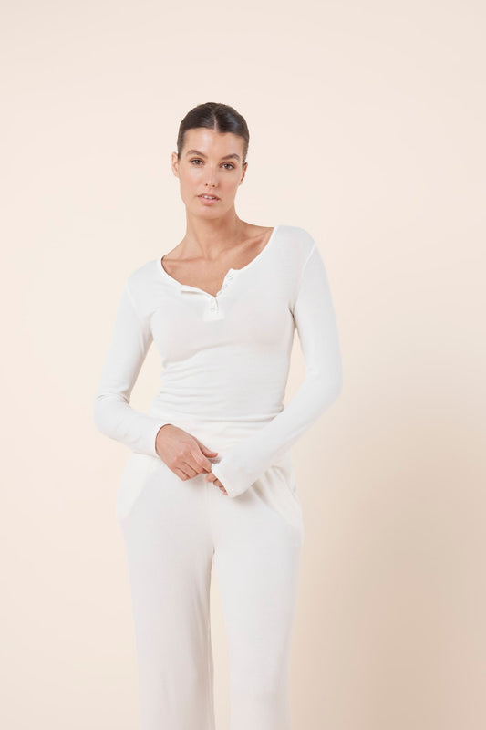 Woman wearing Lille Ribbed Long Sleeve Henley Top Ivory Ecru styled with matching ribbed lounge pants