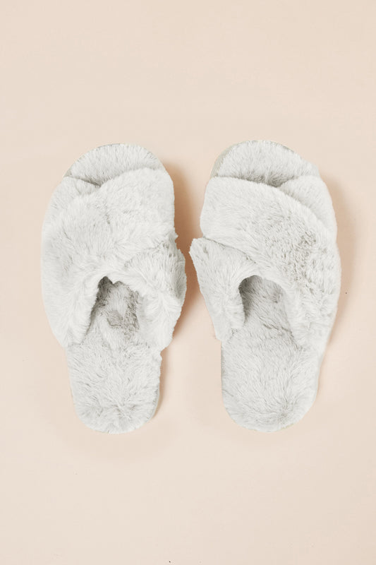 Pair of fluffy Milan Plush Slipper Ivory slippers on a beige background from top view