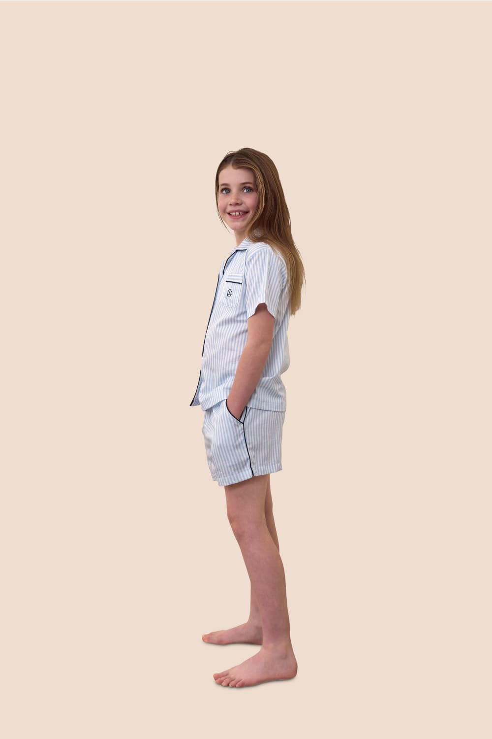 Young girl wearing a light blue pajama set on a beige background