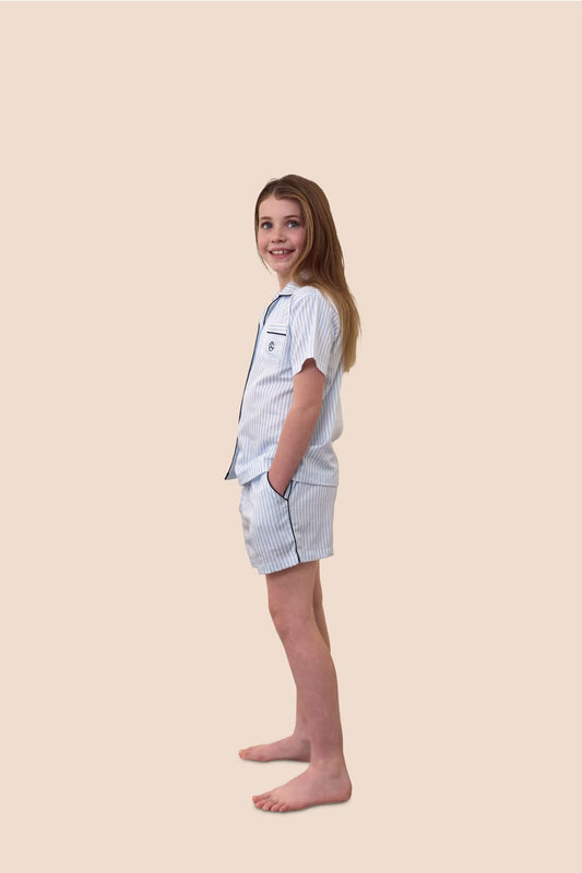 Young girl wearing a light blue pajama set on a beige background