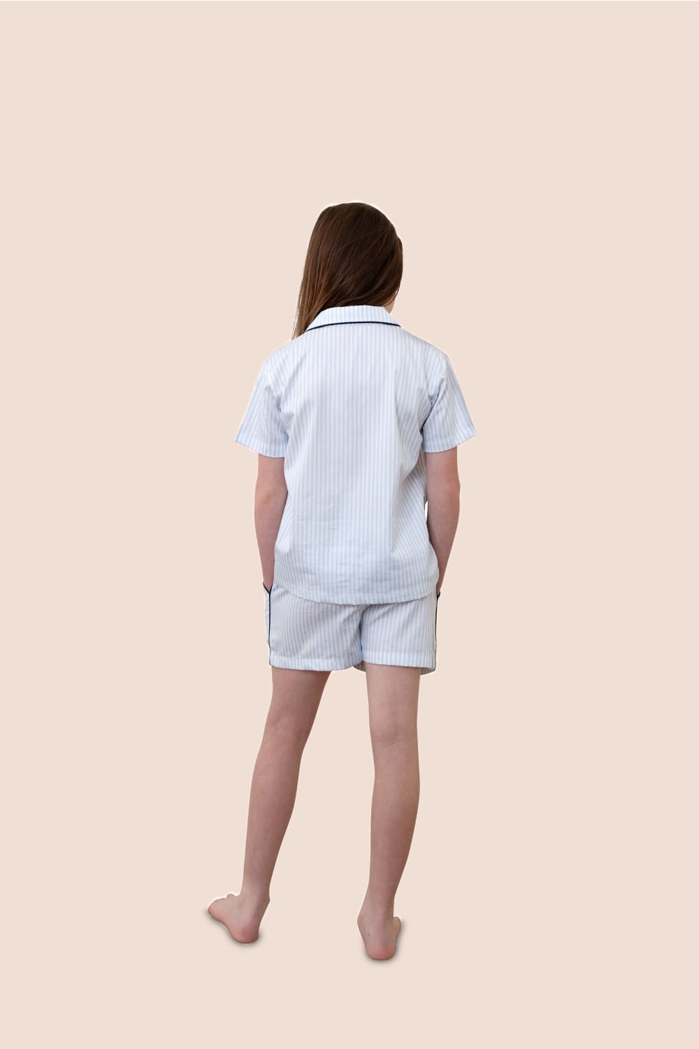 Person wearing a light blue checkered shirt and shorts on a beige background