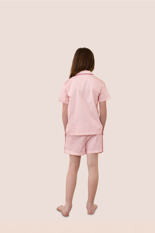 Person wearing a pink pajama set on a light pink background