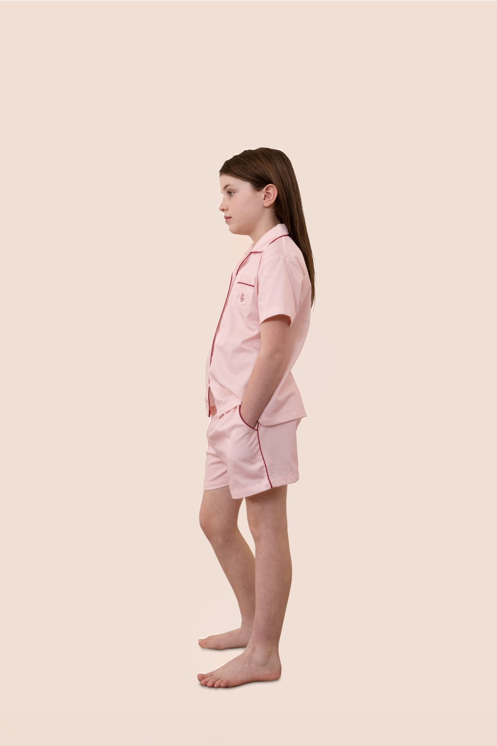 Young girl wearing a pink pajama set against a beige background