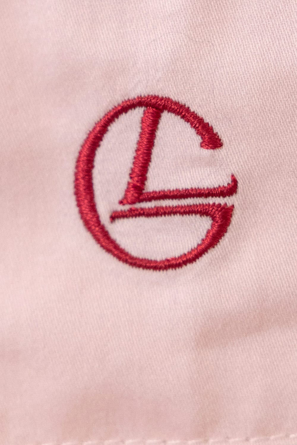 Close-up of a red embroidered logo on a light pink background
