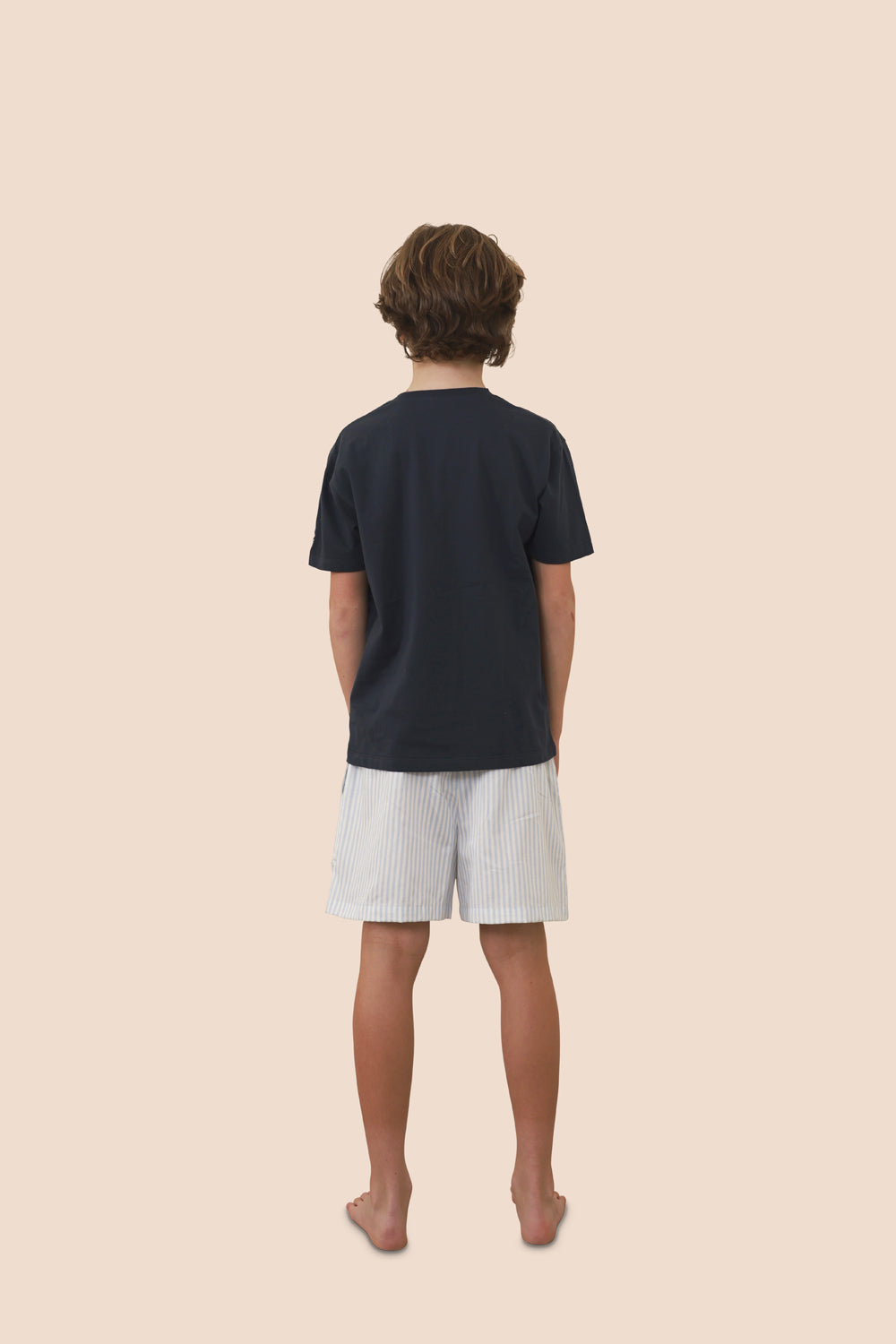 Person wearing a black t-shirt and light-colored shorts on a beige background