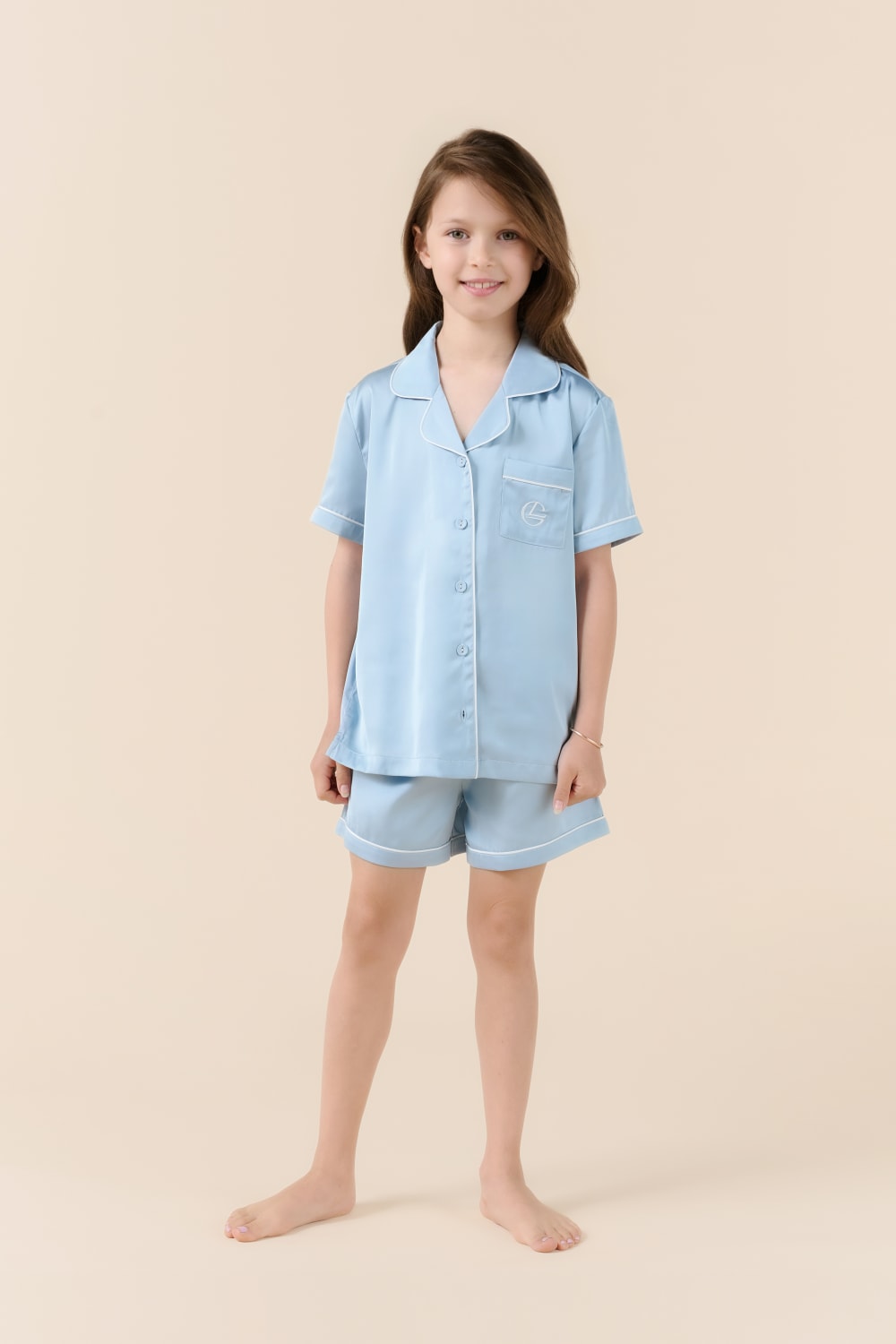 Young girl wearing a light blue pajama set on a beige background