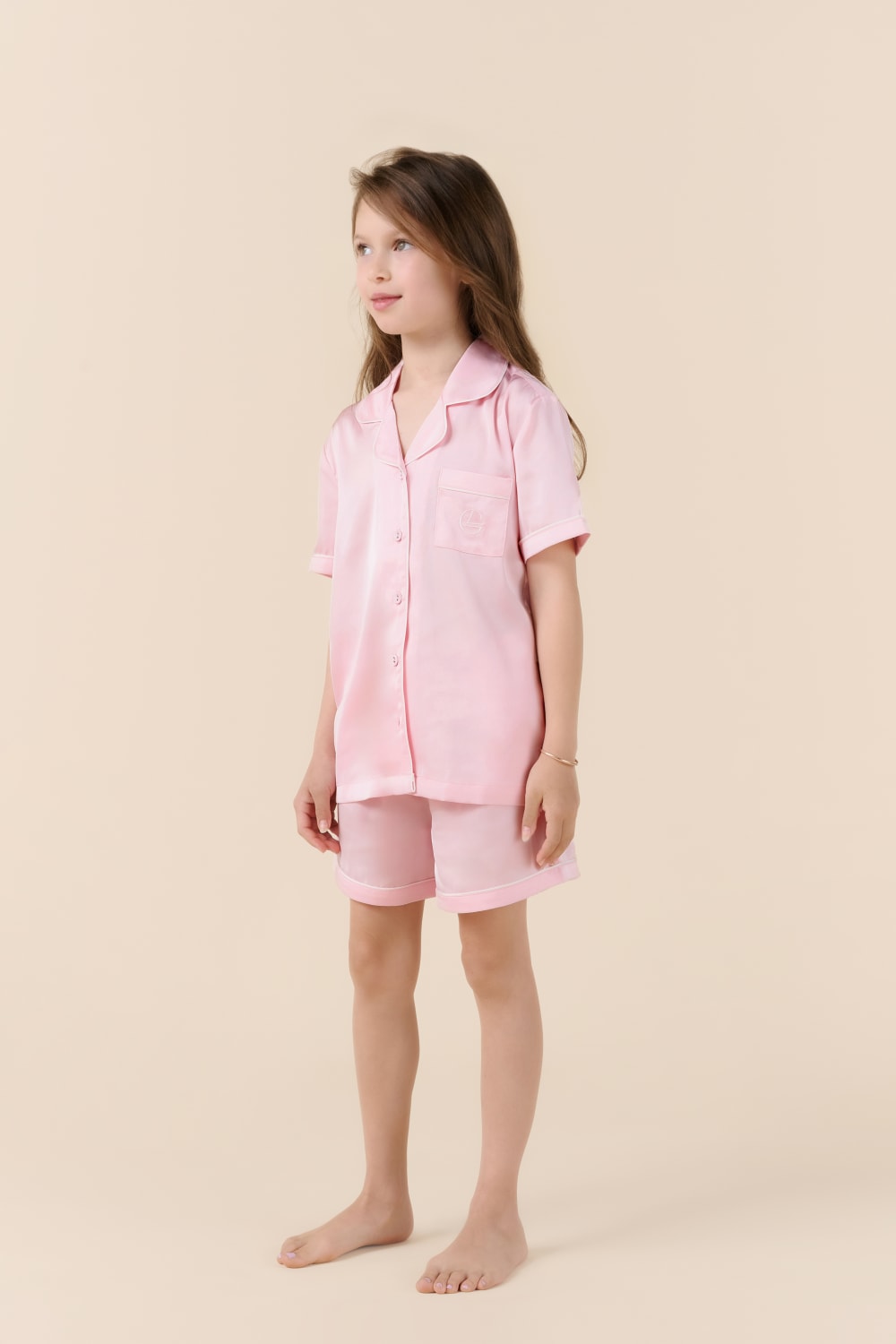 Young girl wearing a pink pajama set on a beige background