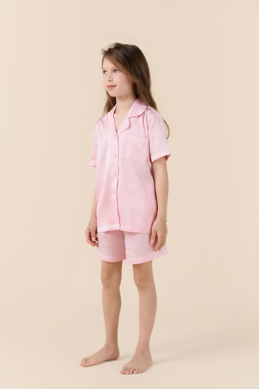 Young girl wearing a pink pajama set on a beige background