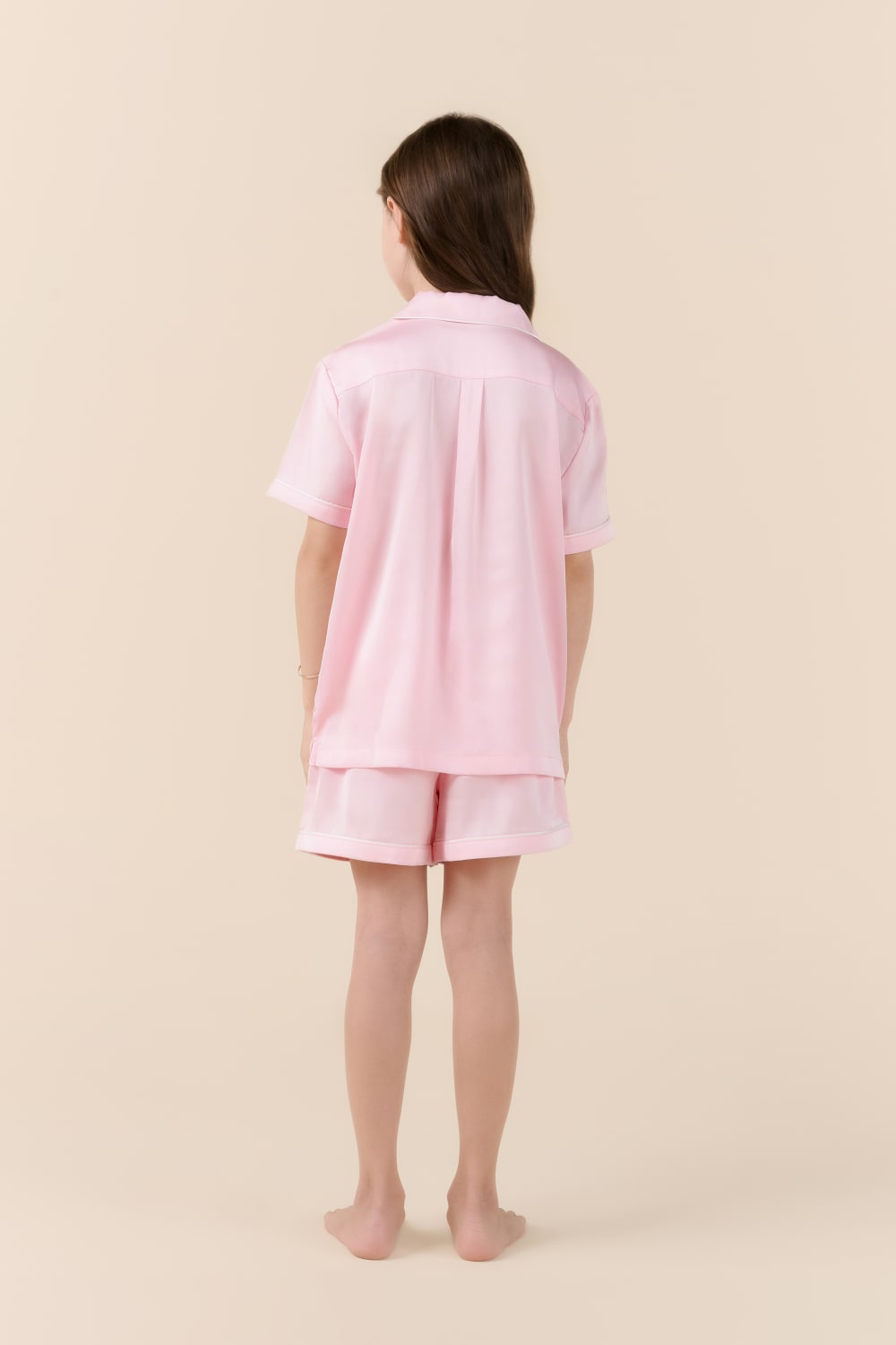 Person wearing a pink pajama set on a beige background