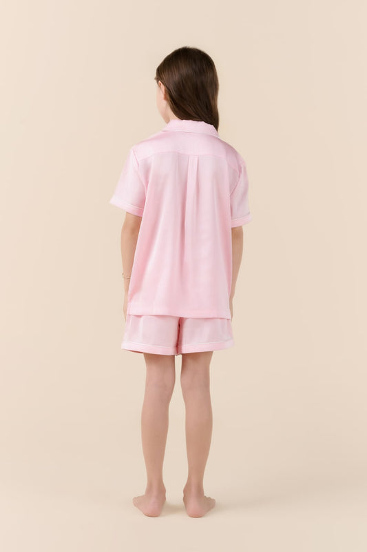 Person wearing a pink pajama set on a beige background