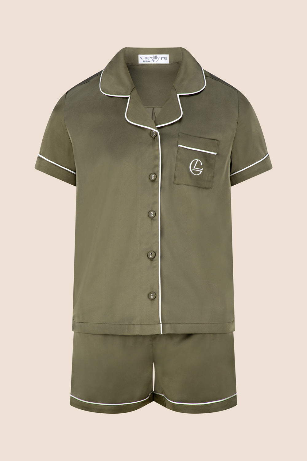 Green pajama set with white piping on a beige background