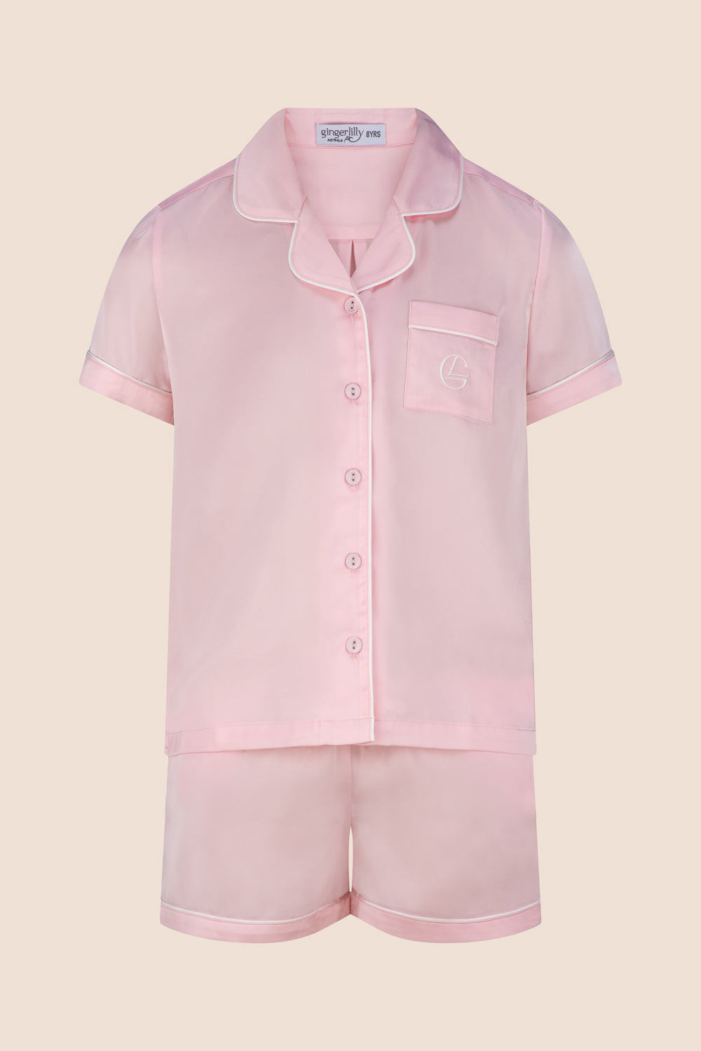 Pink pajama set with shirt and shorts on a beige background