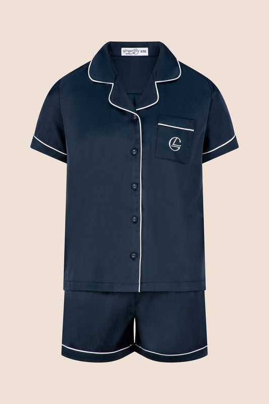 Navy pajama set with white piping on a beige background
