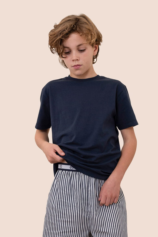 Person wearing a navy blue t-shirt and striped pants on a beige background