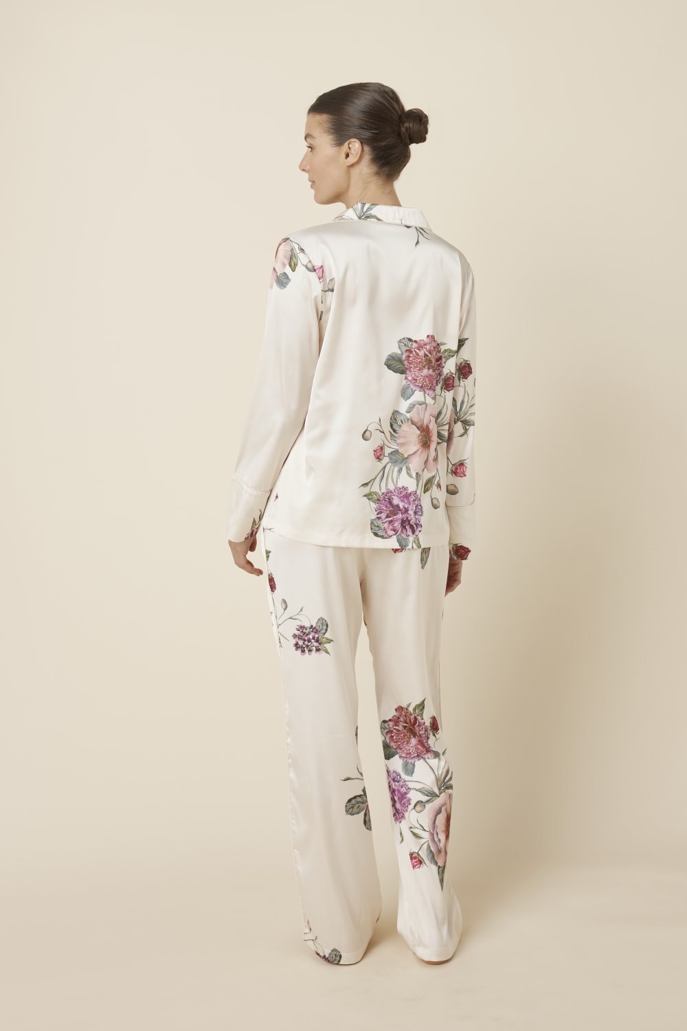 Woman wearing a Ruby Floral Satin PJ set Ivory back view, on a plain background