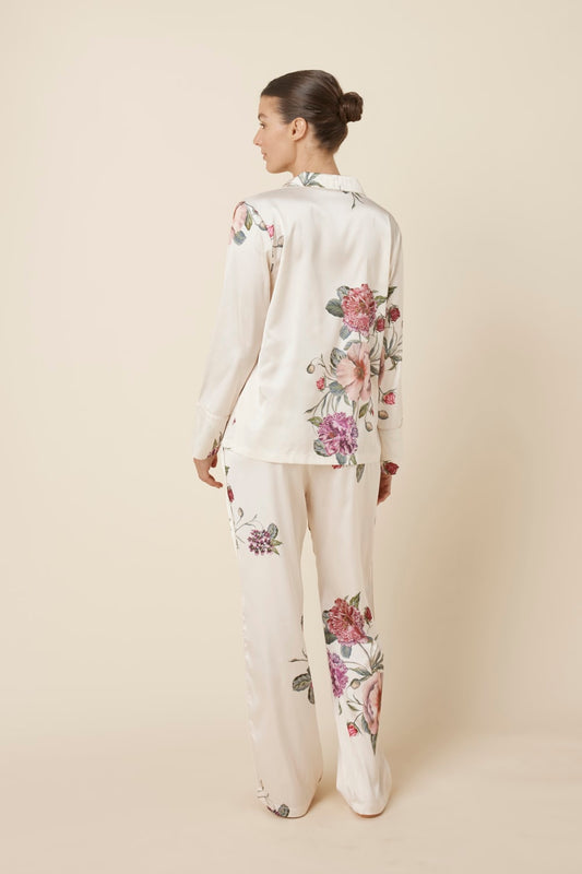 Woman wearing a Ruby Floral Satin PJ set Ivory back view, on a plain background
