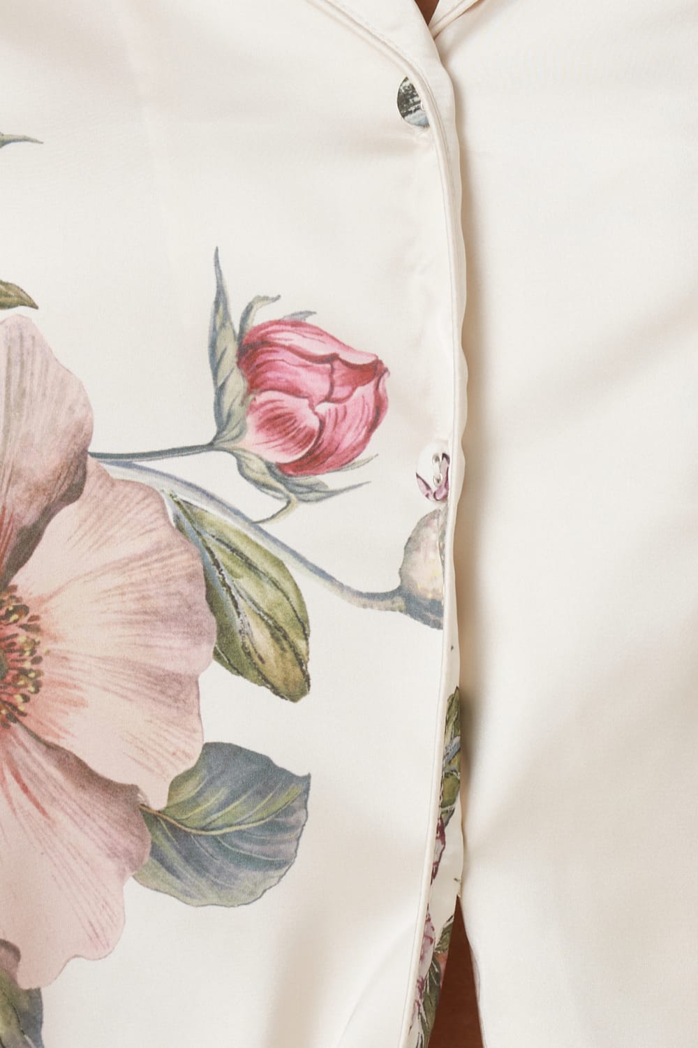 Close-up of Ruby Floral Satin PJ set Ivory detail floral pattern, on garment with pink flowers and green leaves.