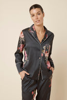 Woman wearing a Ruby Floral Satin PJ set black colour front top view on a beige background