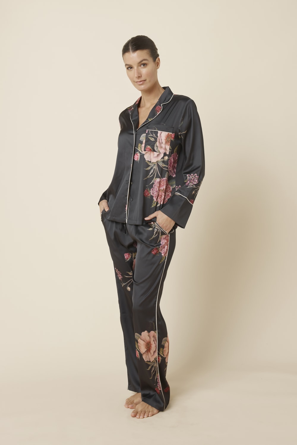 Woman wearing a Ruby Floral Satin PJ set in black side view against a beige background