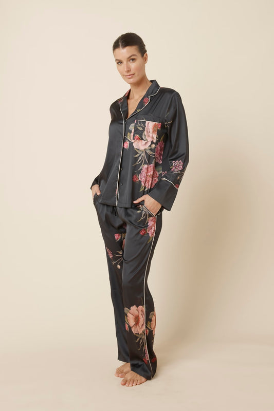 Woman wearing a Ruby Floral Satin PJ set in black side view against a beige background