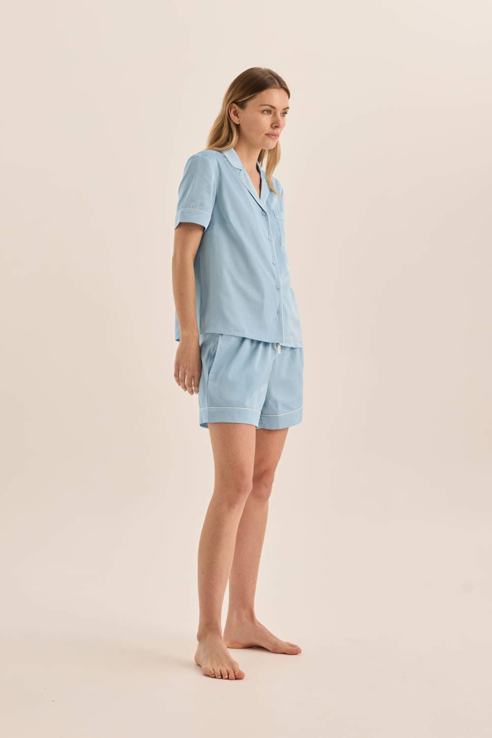 Woman wearing a light blue pajama set on a beige background