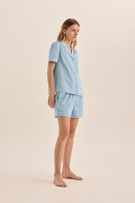 Woman wearing a light blue pajama set on a beige background