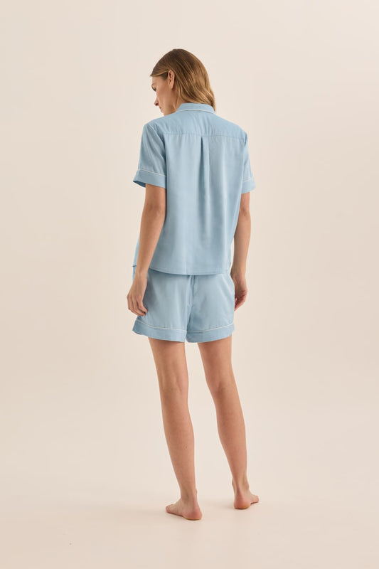 Woman wearing a light blue pajama set on a beige background