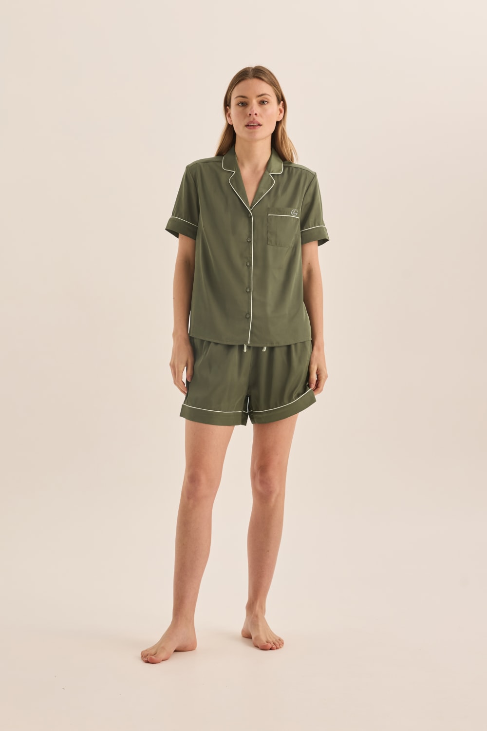 Woman wearing a green pajama set on a beige background