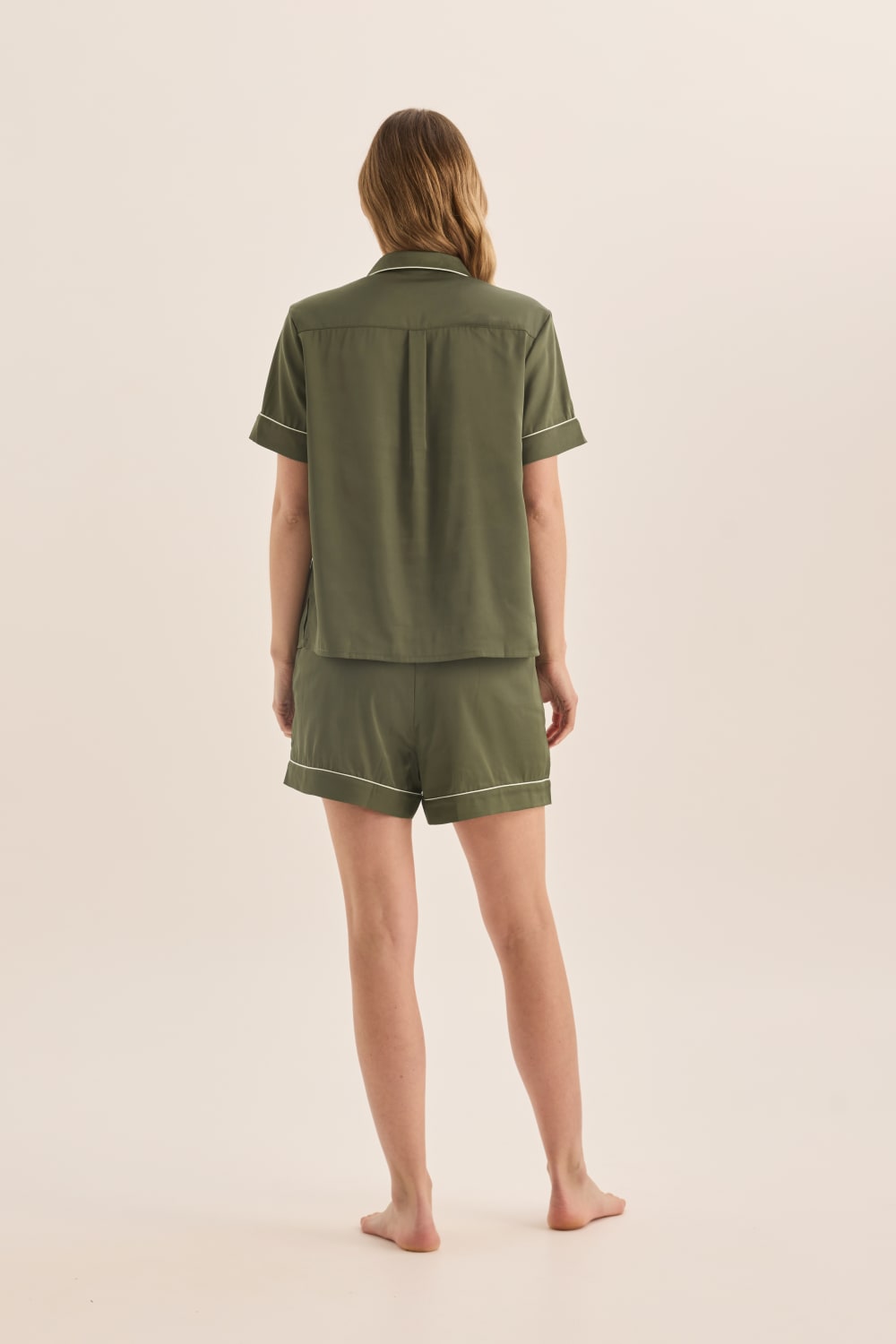 Person wearing a green pajama set on a beige background
