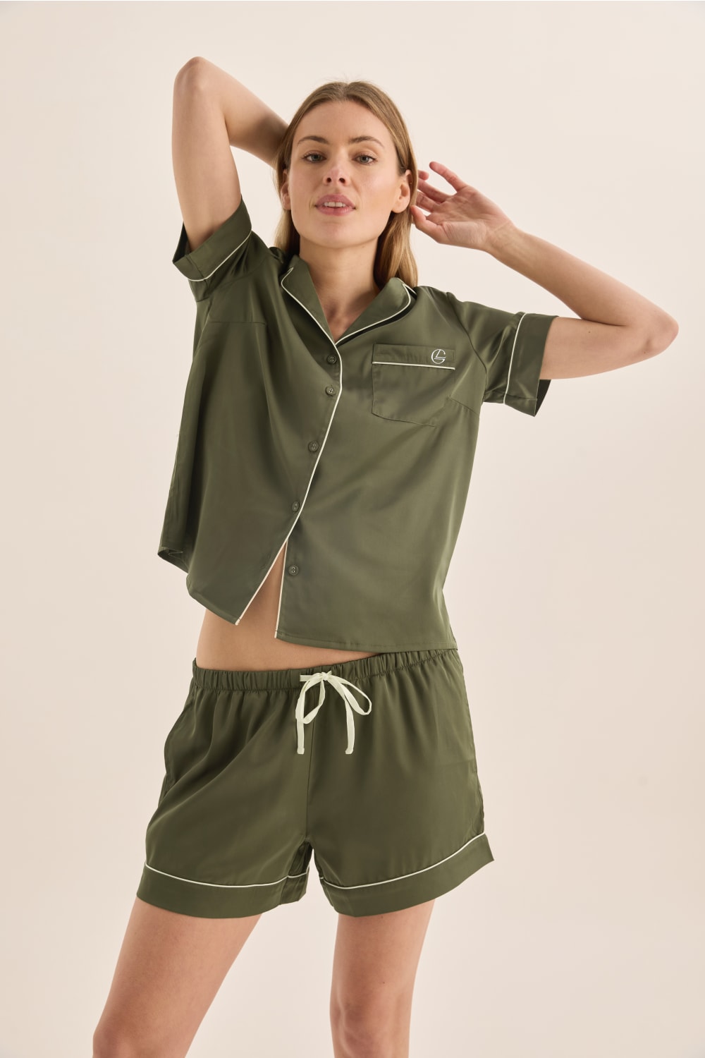 Woman wearing a green pajama set with a beige background