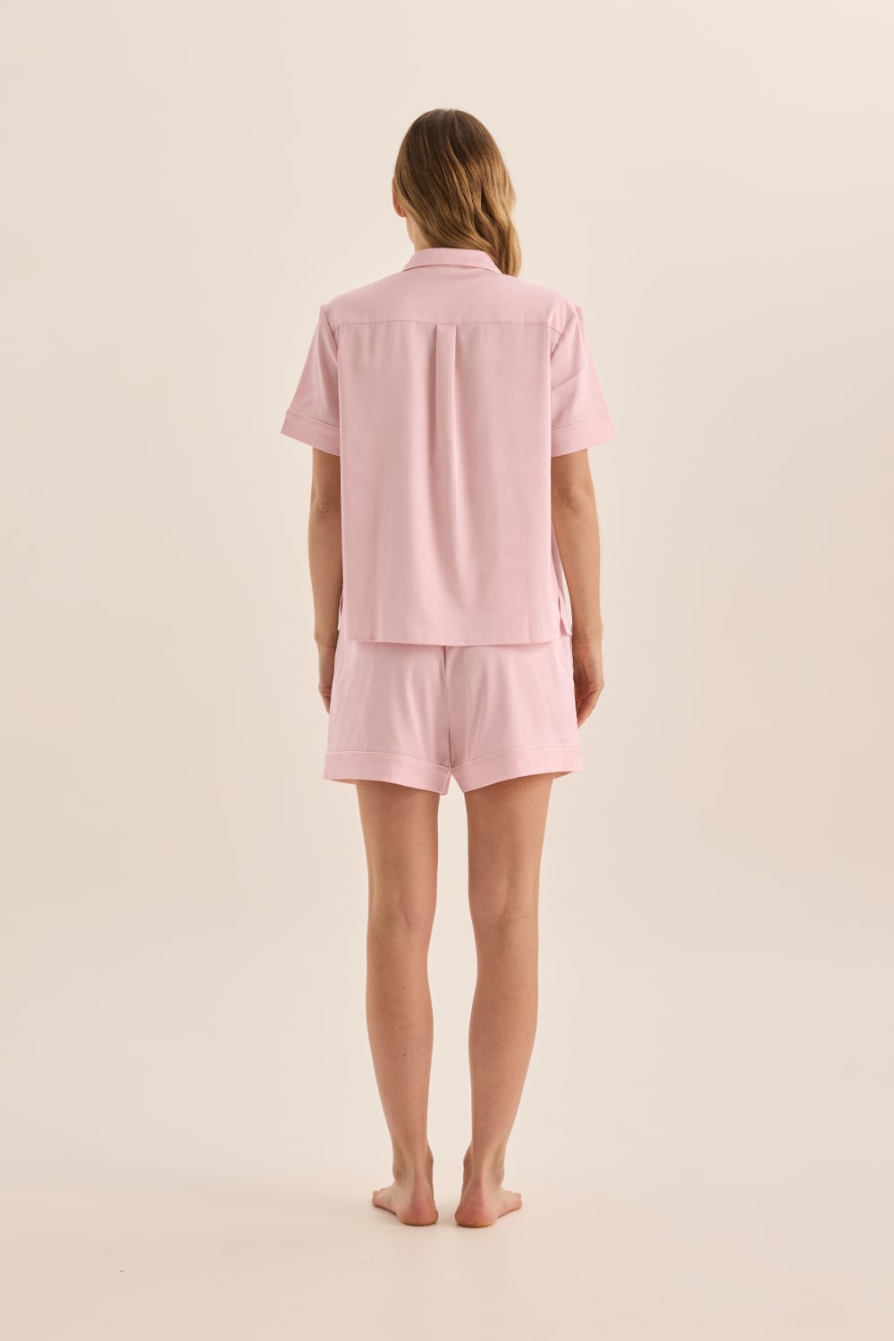 Person wearing a pink pajama set on a beige background