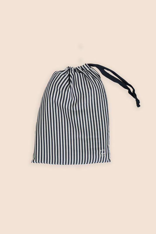 Black and white striped drawstring bag on a beige background