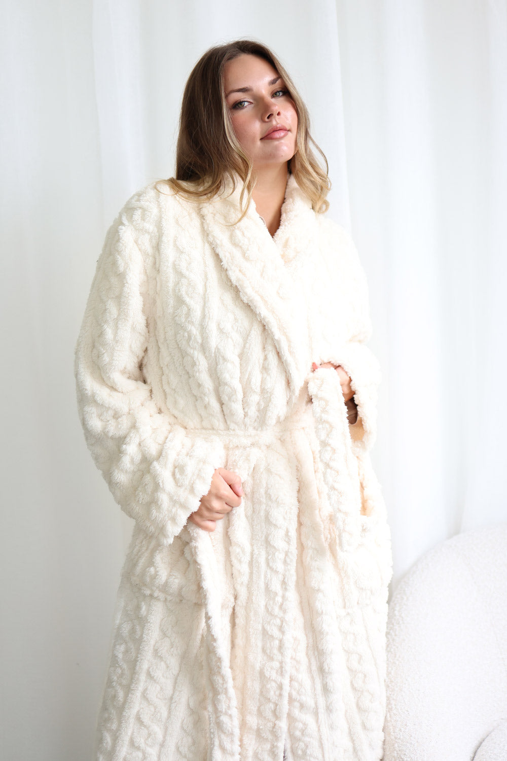 Woman wearing a white textured robe against a plain background